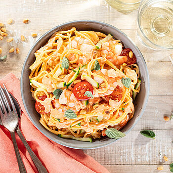 Leckere Spaghetti mit saftigen Garnelen, frischen Zucchini und süßen Cherrytomaten, serviert in einer eleganten Schale